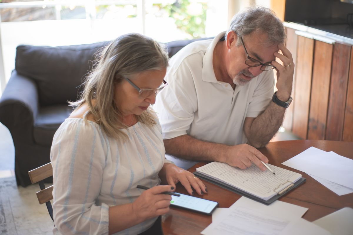 Casal de idosos revisando documentos e planejamento financeiro à mesa